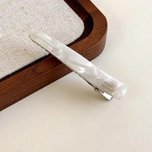 Détail de la pince à cheveux en acétate blanc perle avec lettrage doré France Handmade