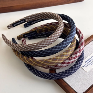 Retro plaid sponge headbands in various colors with handmade label on white surface