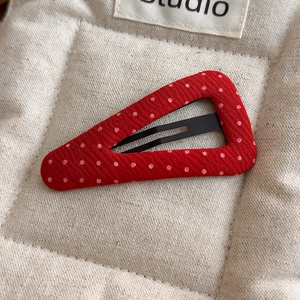 Detailed macro of a red polka dot fabric covered hair clip on quilted background