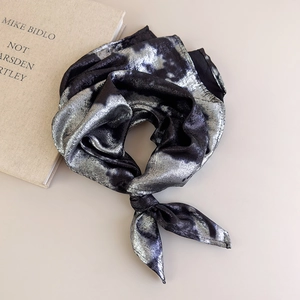 Close-up of knotted black square scarf with silver metallic marble texture on silk satin