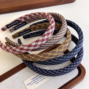 Detailed close-up of retro plaid sponge headbands with handmade labels on wooden tray
