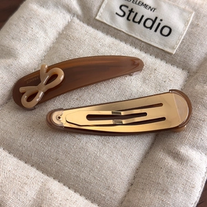 Detail of amber acetate hair clips featuring France Handmade logo and bow accent