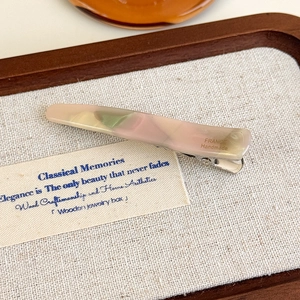 Détail d'une pince à cheveux en acétate avec motif marbré rose et vert fait main