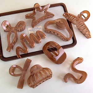 Translucent amber irregular geometric hair claws with star and wave shapes on wooden tray