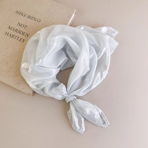 Detail showing elegant knot of pearl-white translucent silk scarf on minimalist book