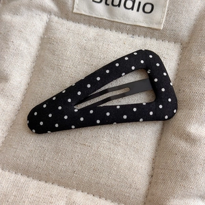 Detailed macro view of a fabric-covered polka dot hair clip on a soft textured background