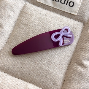Detail of purple acetate bow hair clip with golden France Handmade logo lettering