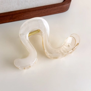 Macro shot of marble textured resin hair claw clip with golden spring mechanism