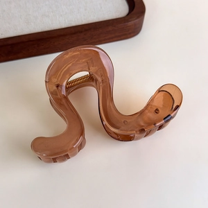 Close-up of brown amber pattern wave hair claw with a durable gold metal spring