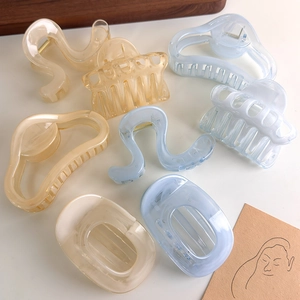 Variety of semi-transparent amber and blue resin hair claws on a minimalist white surface