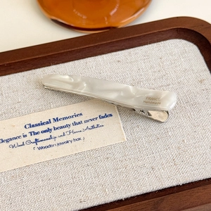Détail de la barrette en résine motif marbre avec base en métal argenté et gravure artisanale