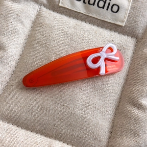 Detail of handmade France gold-label acetate hair clip with bow and engraved text