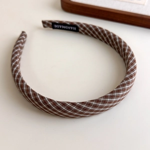 Detailed close-up of a plaid pattern headband with a handmade label on the inner side