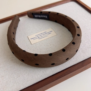 Détail d'un serre-tête marron à pois avec texture sergée et étiquette faite main