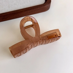 Close-up of translucent amber bow hair claw clip with strong metal spring detail