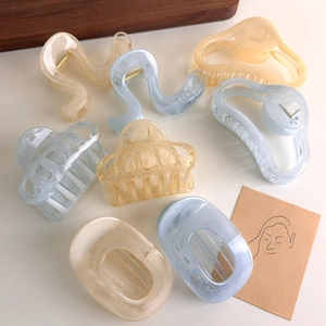 Detail view of translucent marble-textured hair claws in blue, cream and amber tones