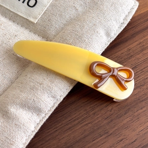 Detail of yellow acetate hair clip featuring a brown bow and France Handmade engraving