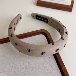 Détail du serre-tête artisanal en tissu avec motifs nœuds et étiquette logo noire