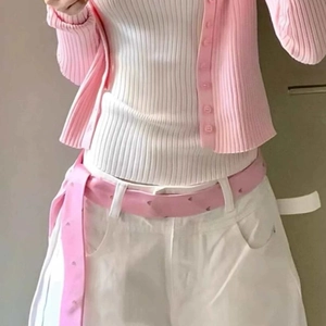 Close-up of a pink striped belt styled with a knit cardigan and white casual trousers