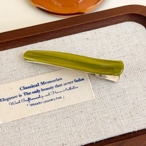 Détail d'une pince à cheveux verte en acétate avec gravure dorée France Handmade