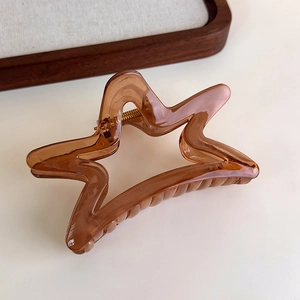 Macro shot of an amber star-shaped hair claw clip made of polished resin on a wooden tray