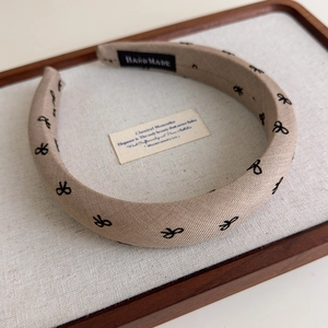 Détail d'un serre-tête artisanal en tissu avec nœuds brodés et étiquette interne