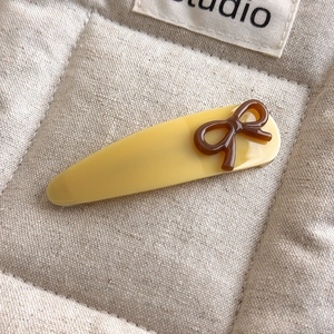 Detail of yellow acetate hair clip featuring a brown bow and France Handmade engraving