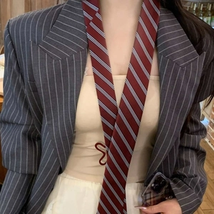Detail shot of a wine red striped tie paired with a grey pinstripe suit jacket