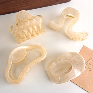 Detailed view of four cream-colored resin hair claws with marble texture in various shapes