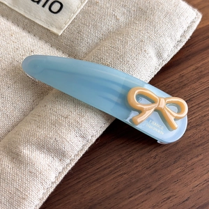 Macro detail of handmade light blue acetate bow hair clip with gold France lettering