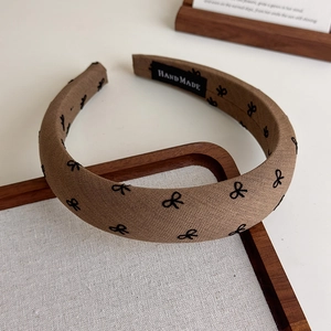 Détail d'un serre-tête rembourré marron avec motifs nœuds et étiquette HANDMADE interne