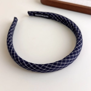 Detail of blue plaid sponge headband showing the handmade label and soft fabric texture