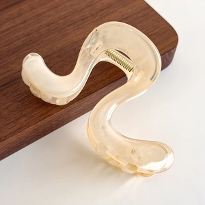Detail shot of wavy cream beige translucent hair claw clip with golden metal spring