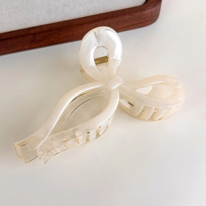 Macro view of bow hair claw with elegant cream marble texture and golden spring