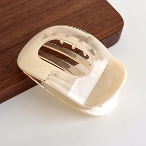 Detail view of a translucent cream-colored hair claw clip with a hollow oval design
