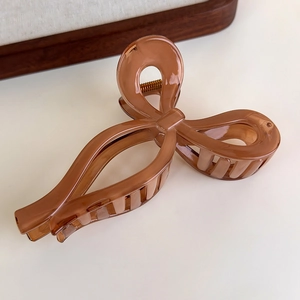 Detail of amber brown bow hair claw clip made of polished resin with strong metal spring