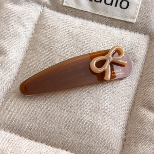 Close-up of tortoise acetate clip with beige bow and gold France Handmade engraving