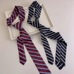 Detailed macro view of burgundy and black striped satin neckties in a beige display tray