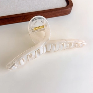 Detail view of cream marble hair claw clip with golden spring and wavy resin texture