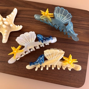 Detailed close-up of acetate shell, starfish, and whale hair claws on wood background