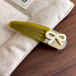 Close-up of green acetate hair clip with white bow and France Handmade logo detail