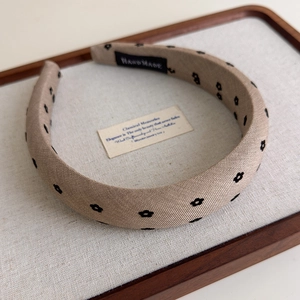 Détail d'un serre-tête en tissu beige à motifs floraux et étiquette faite à la main