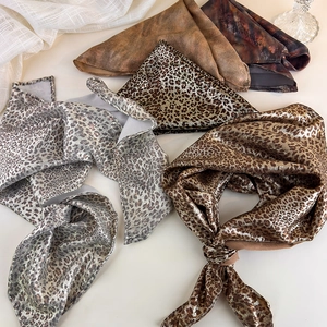 Detailed view of leopard print and metallic silk scarves collection in various colors