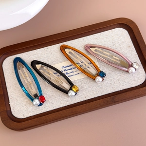 Detailed view of four colorful resin hair clips with pearls and rhinestones on wood