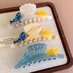 Detailed shot of ocean-themed hair claws with seashell and starfish pearlescent finish