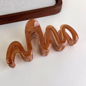Detail of amber translucent wavy hair claw clip made of premium resin on beige background