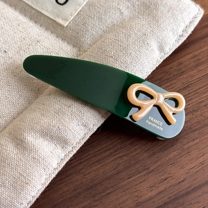 Detail of dark green acetate hair clip with khaki bow and golden France logo