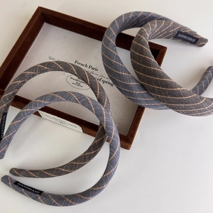 Detail of handmade striped fabric headband with wash label on a wooden display case