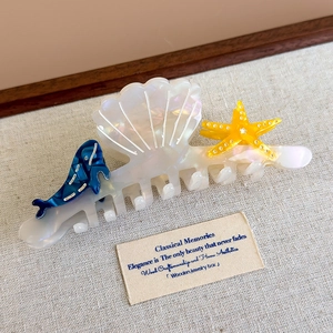 Detail of acetate shark hair claw featuring shell, starfish and dolphin ocean elements
