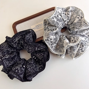 Elegant set of black and white paisley print fabric scrunchies on a wooden tray
